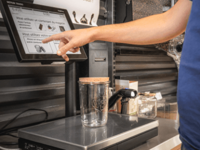 Balance VRAC épicerie et magasin bio un homme pèse un récipient de riz sur une balance tactile dans une épicerie bio