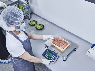 Balance de contrôle dans l’agroalimentaire une femme pèse un carton de crevettes sur une balance mettler toledo